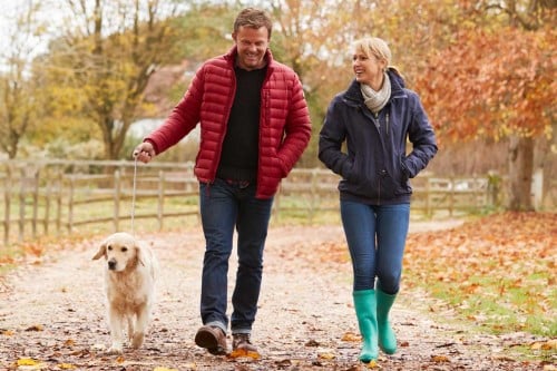 Couple walking dog in park